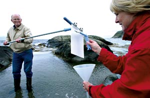 SINTEF-forsker Kjell Josefsen i sving med å samle opp bakterier fra havoverflaten. Kollega Nina Øino skraper av den tynne filmen som legger seg på kosten. Foto: Geir-Otto Johansen