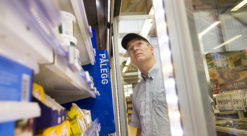 Mann med med blå skjermlue/caps ser inn i kjøledisk på Rema-butikk