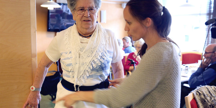 Beboer ved Laugsand helse- og velferdsenter, Skjoldvor Måsøval, får forskerhjelp til å justere beltet som skal sende ut en alarm dersom hun er uheldig og faller. Foto: Kjersti Fikse Ness, Adresseavisen