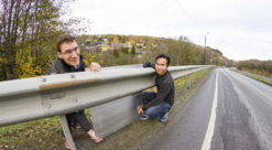 Two men show how a noise barrier will look when integrated in guardrails.