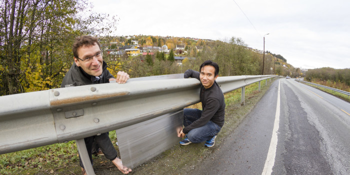 Standard guardrails are often installed where the ground falls away from the roadside. Houses that are to be screened from noise in such locations usually lie somewhat lower than the source of noise. Taking this as the basic situation, SINTEF scientists Dirk Nolte (left) and Nguyen Hieu Hoang investigated how aluminium noise-barriers could be directly mounted on guardrails. Photo: SINTEF/Thor Nielsen