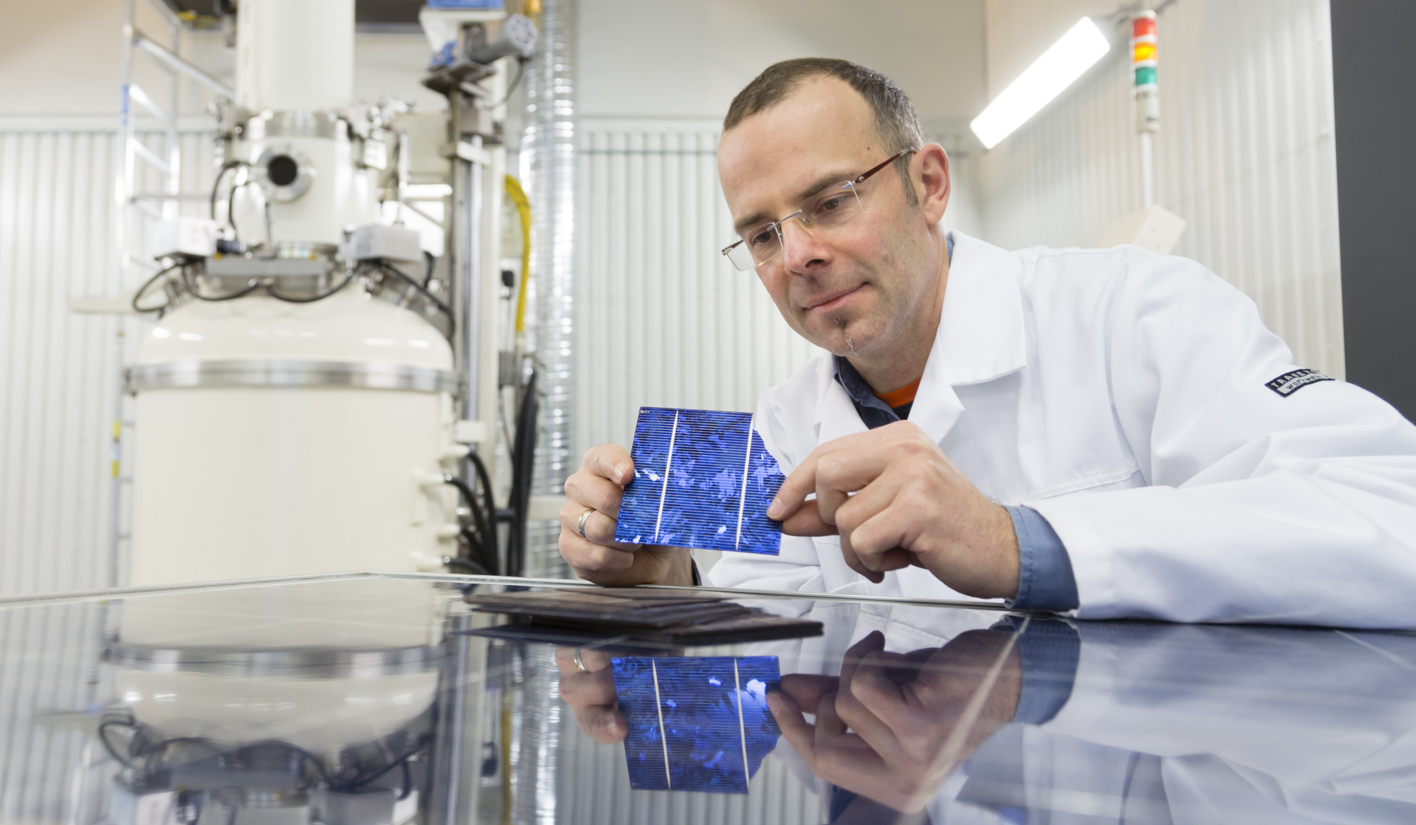 Forsker Martin Bellman i SINTEF i laboratoriet, hvor han viser fram solceller som skal gjenbrukes.