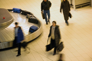 Travelers collecting luggage from airport baggage carousel.
