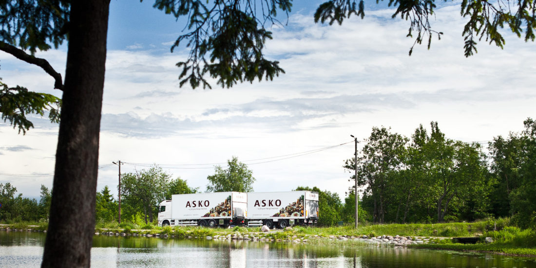 Trailer med logoen ASKO kjører langs norsk skogsvann.
