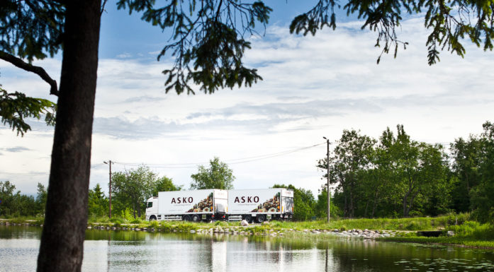 Trailer med logoen ASKO kjører langs norsk skogsvann.