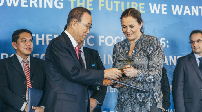 FNs generalsekretær Ban Ki-moon i samtale med SINTEF-sjef Alexandra Bech Gjørv i FN-bygningen i New York, foran himmelblå vegg, dekorert med innskriften "Powering the future we want"