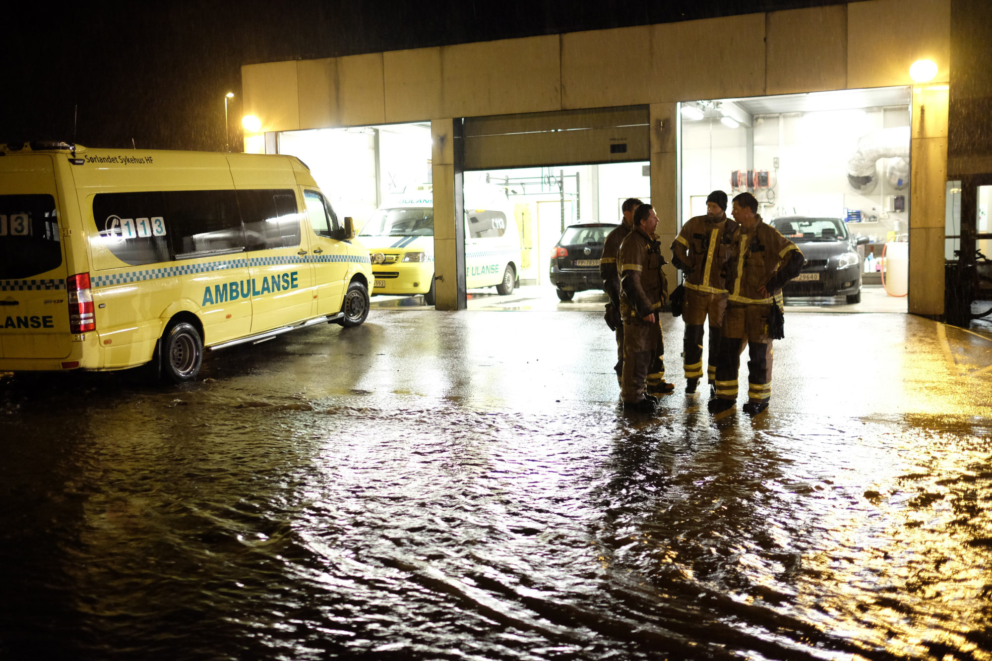 Ambulanse og brannfolk ses inne i oversvømmet underetasje ved sykehus.