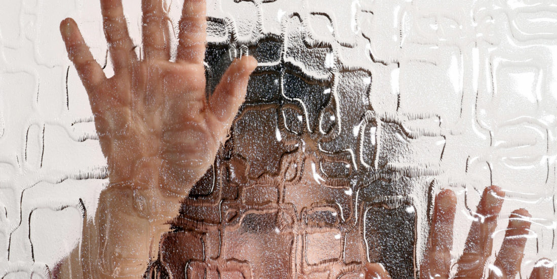 Kvinneansikt og hender fotografert gjennom ruglet glass