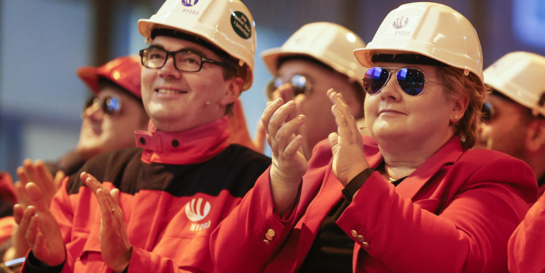 Gruppe mennesker med oransje og røde jakker og hvit hjelm på hodet, applauderer. en av dem er statsminiser Erna Solberg.
