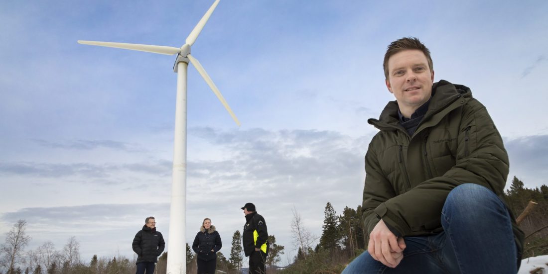Fire personer ses foran 30 meter høy vindturbin