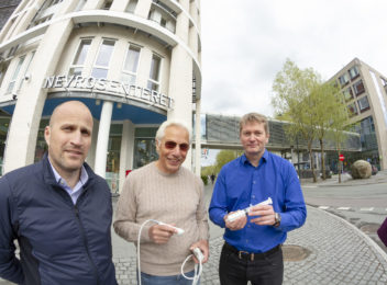 Bilde av tre menn foran moderne bygg.