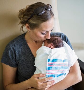 Fødsel: Foto viser en kvinne som holder en baby på fanget. 