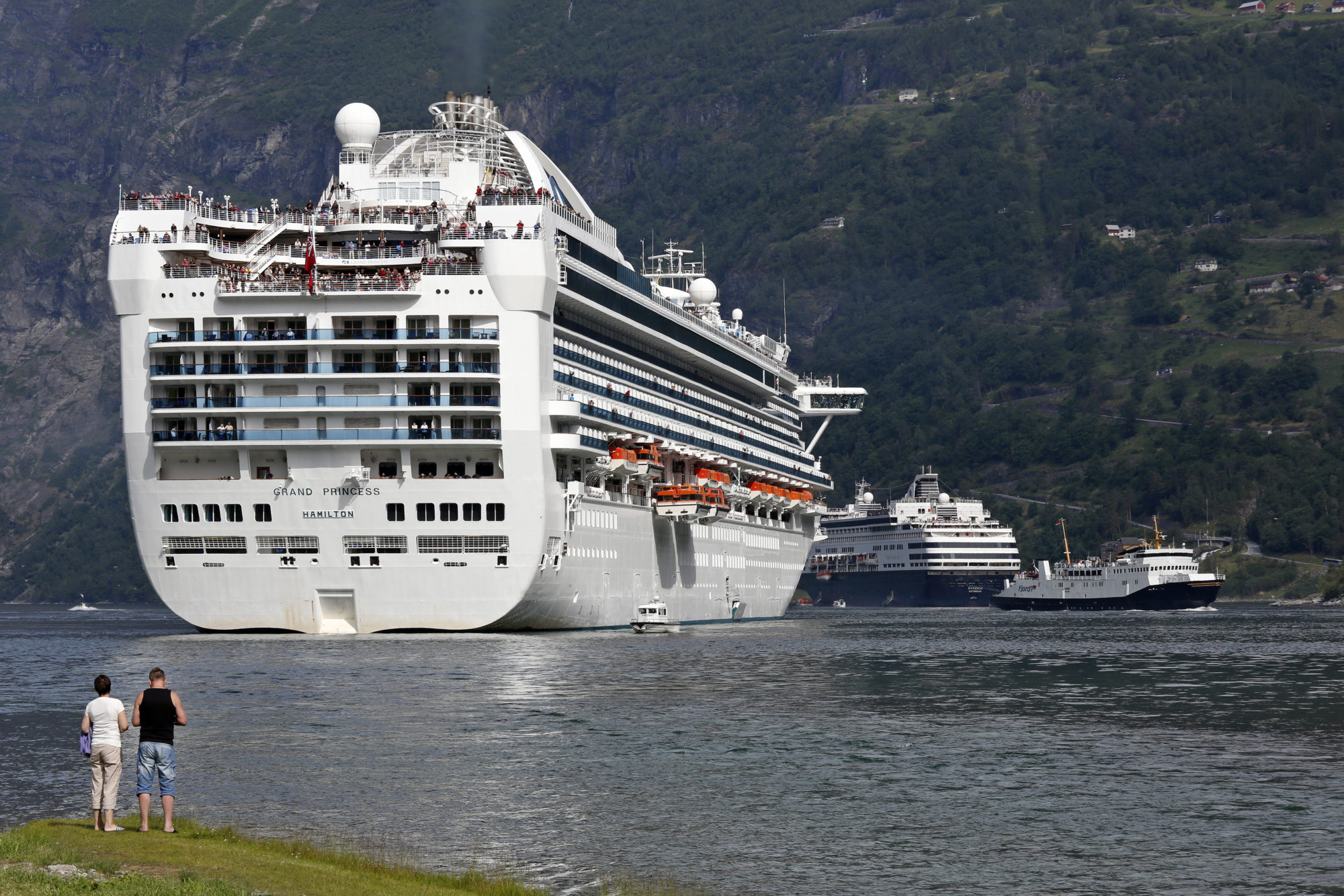 Akterenden av svært cruiseskip ruver opp nær land i Geiranger