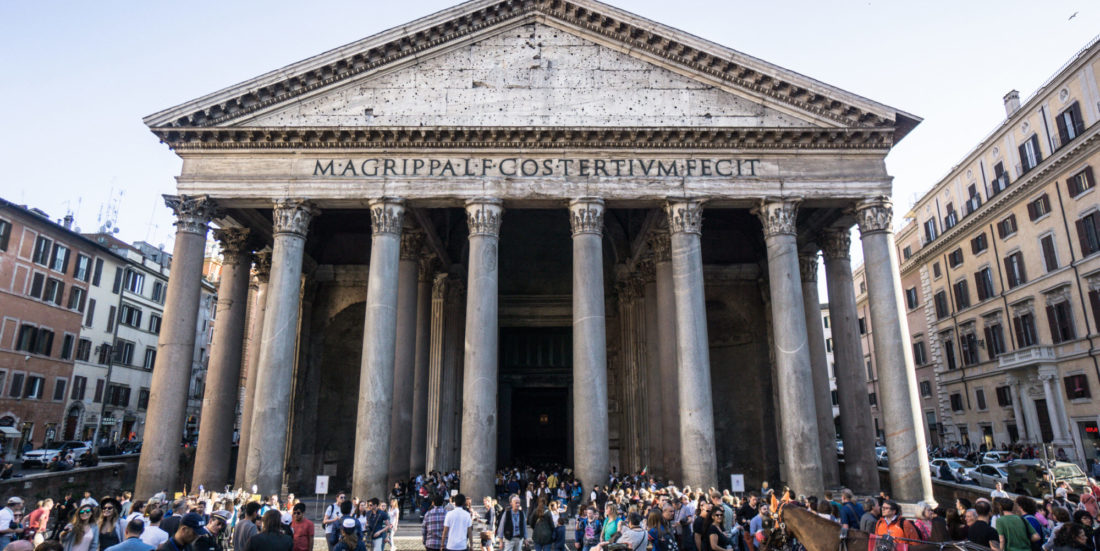 Det gamle betongbygget Pantheon i Roma fotografert mot søylene ved inngangspartiet. Store mengder turister skimtes i forgrunnen.
