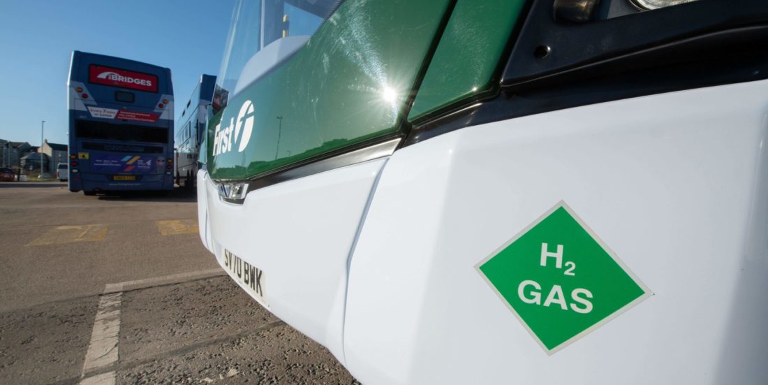 Hydrogen energi : Detaljbilde av fronten på hvitlakkert buss med grønt merke som har teksten "H2 Gas"