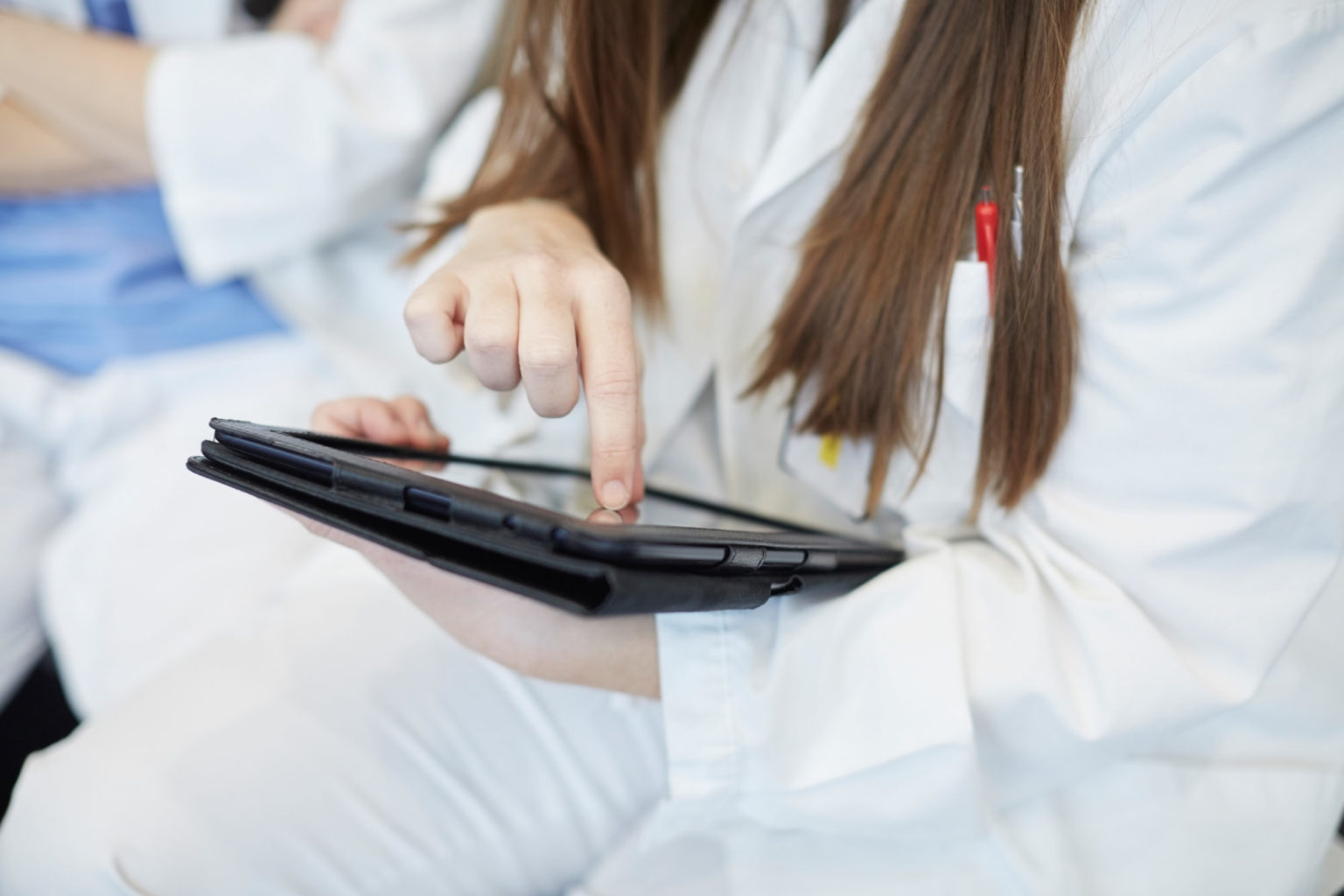 Kvinne i hvit helseuniform holder laptop i fanget