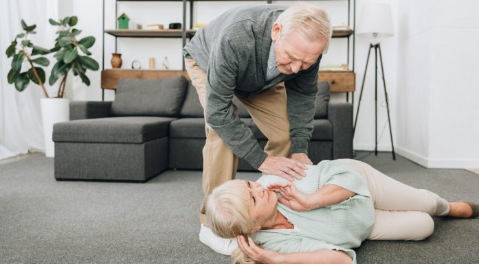 Bildet viser eldre mann som hjelper kvinne på gulvet.