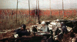Fargebilde i rødbrune toner av soldater i skyttergrav under første verdenskrig.