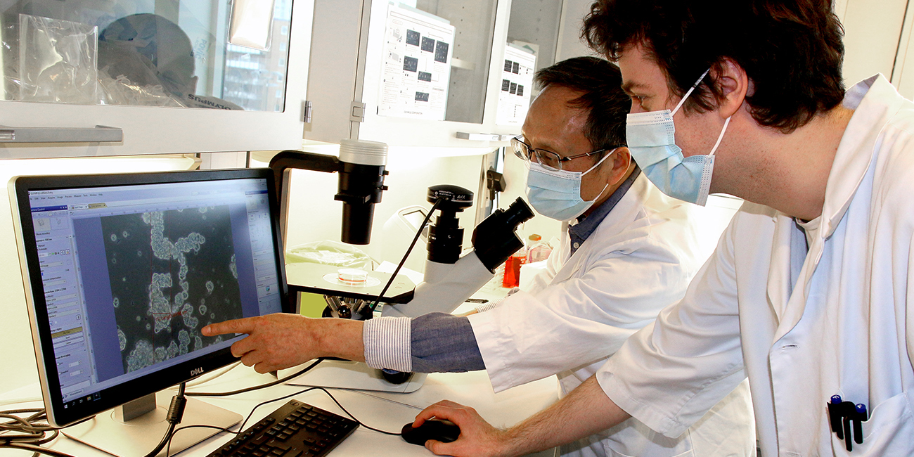 Foto. To forskere ser på mikroskopbilder på laben.