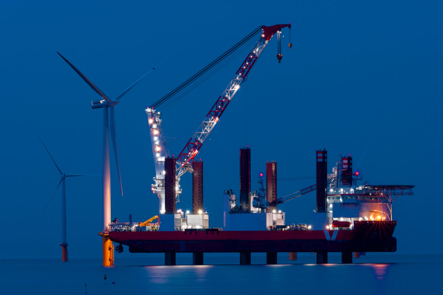 Nattbilde der vi ser opplyst rigg montere vindturbiner til havs.