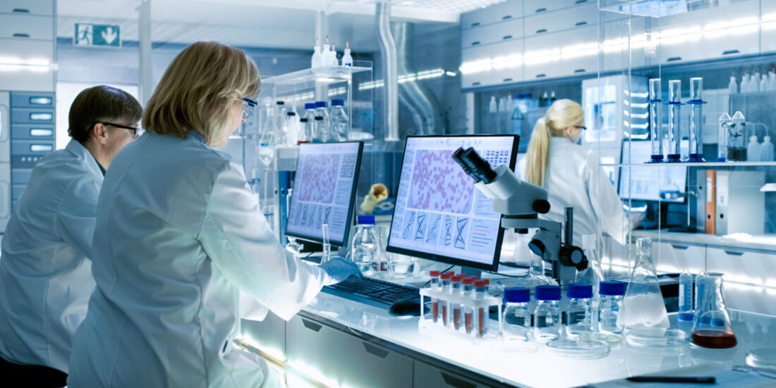 Bilde fra laboratorium der menn og kvinner i hvite frakker sitter foran hver sin dataskjerm