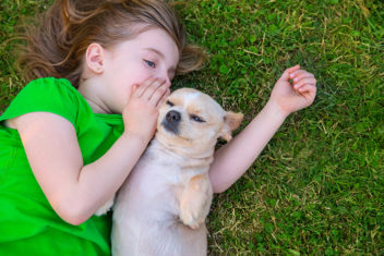 Bildet viser ei lita jente som koser med en hund