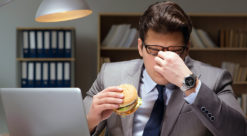 illustrasjonsfoto: Forretningsmann kvier seg mens han spiser hamburger