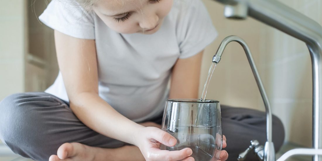 Barn tapper rent drikkevann på kjøkken