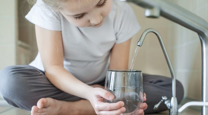 Barn tapper rent drikkevann på kjøkken