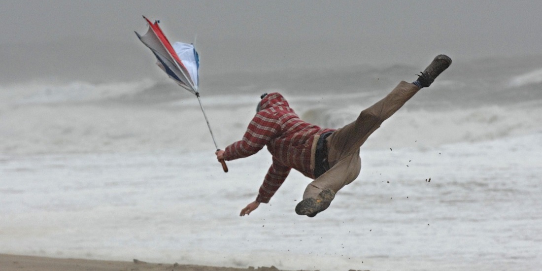 Kaos. Bildet viser en mann som mister fotfestet i vinden.
