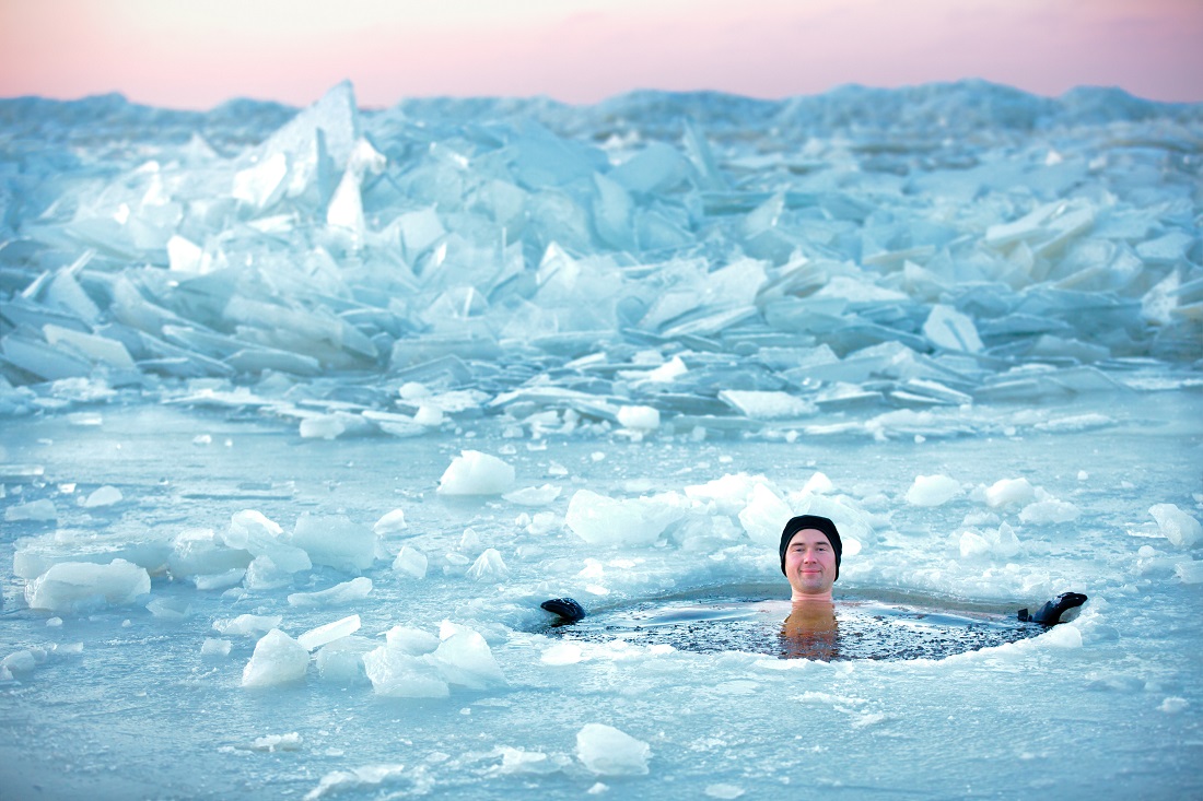 BIldet viser en mann som bader i et hull i isen.
