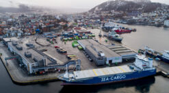Dronefoto av Bergen havn. I forgrunnen ligger stort lasteskip med blåmalt skrog.