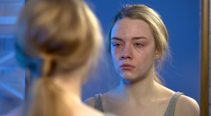Grubling. Illustrasjonen viser ei deprimert jente foran speilet.