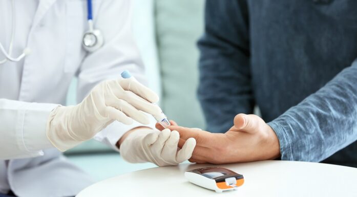 Diabetes. Bildet viser lege som tar blodprøve i fingeren til pasient.