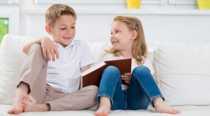Lesing. Bildet viser to barn som leser i sofaen.
