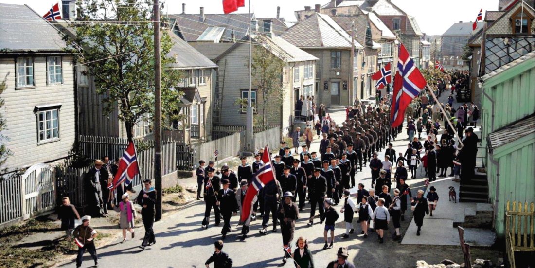 Bilde av mange mennesker i Vestfjordgata i Svolvær som feirer med norske flagg i henndene.