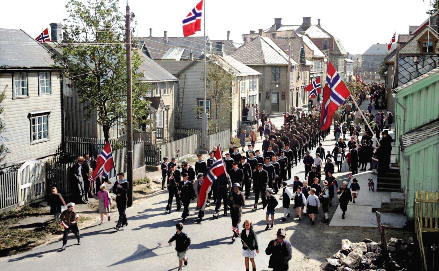 Bilde av mange mennesker i Vestfjordgata i Svolvær som feirer med norske flagg i henndene.
