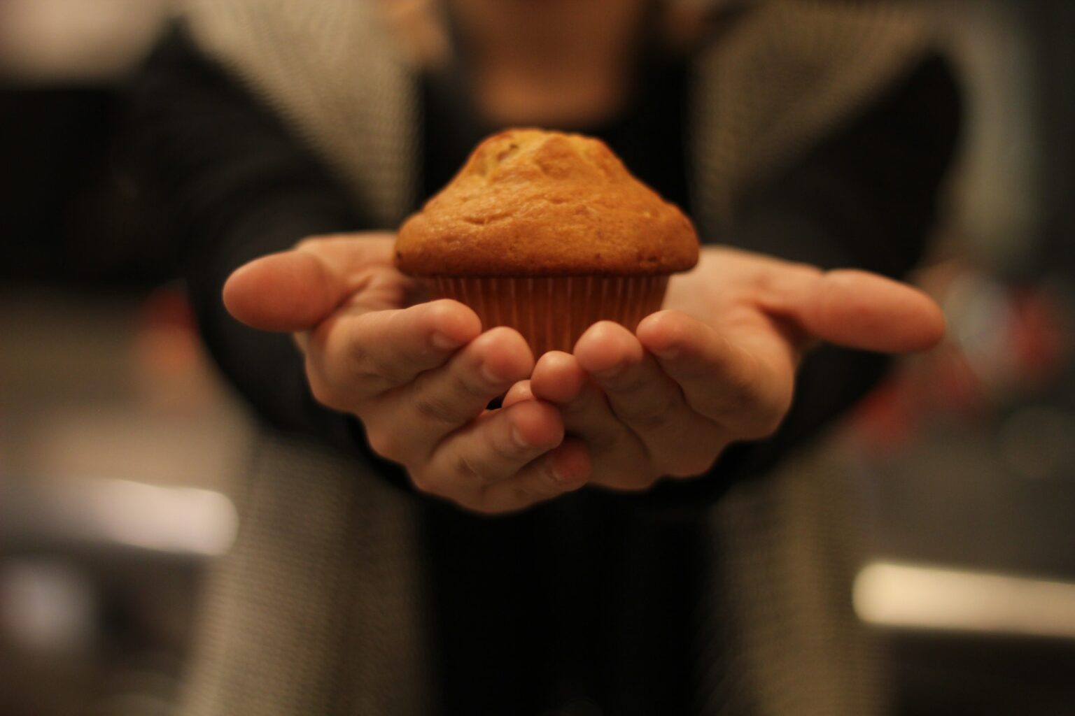 En person som holder en muffins i hendene.