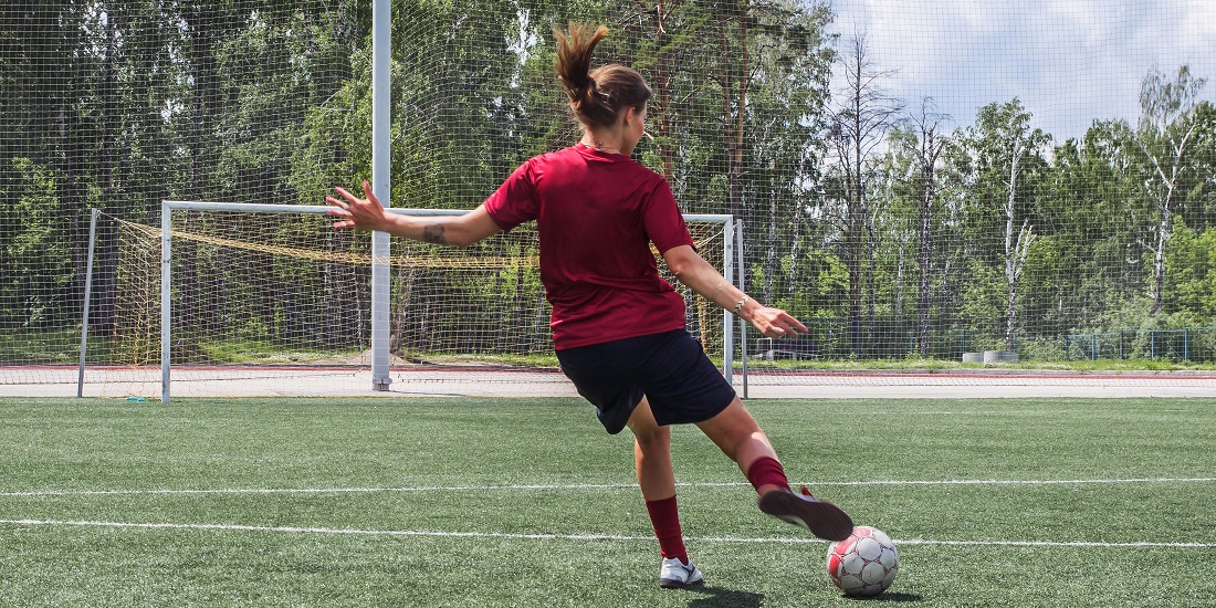 Navn. Bildet viser kvinne som sparker fotball mot mål.