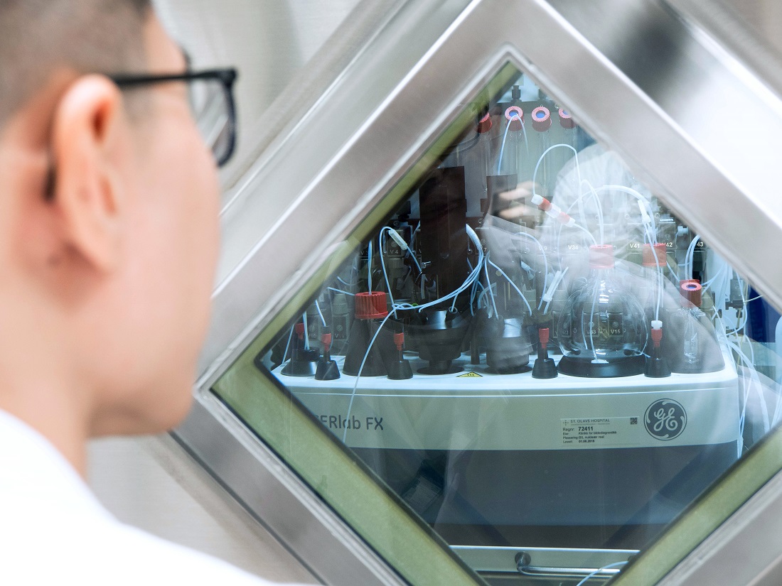 Teranostikk. Bildet viser Tengzhi Liu foran et glasskap med laboratorieutstyr.