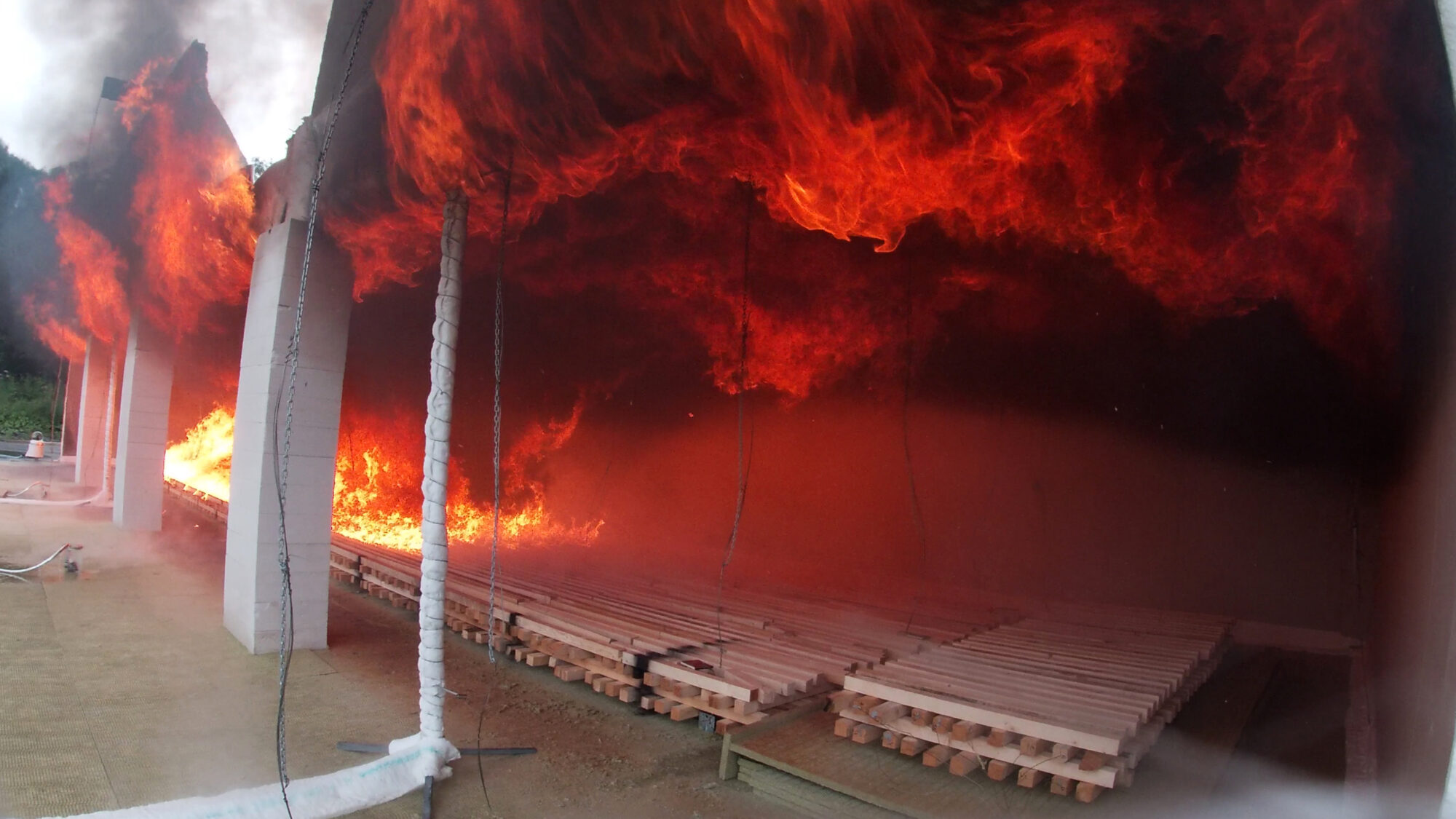 Fuoco di legno duro: il fuoco si diffonde lungo il soffitto di legno duro.  In questo esperimento la parete di fondo è ricoperta di cartongesso.