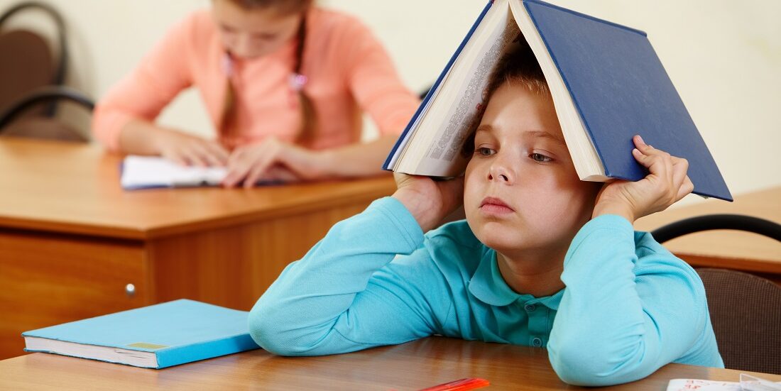 Ordforrådet. Bildet viser en gutt med ei bok på hodet. I bakgrunnen ei jente som leser.