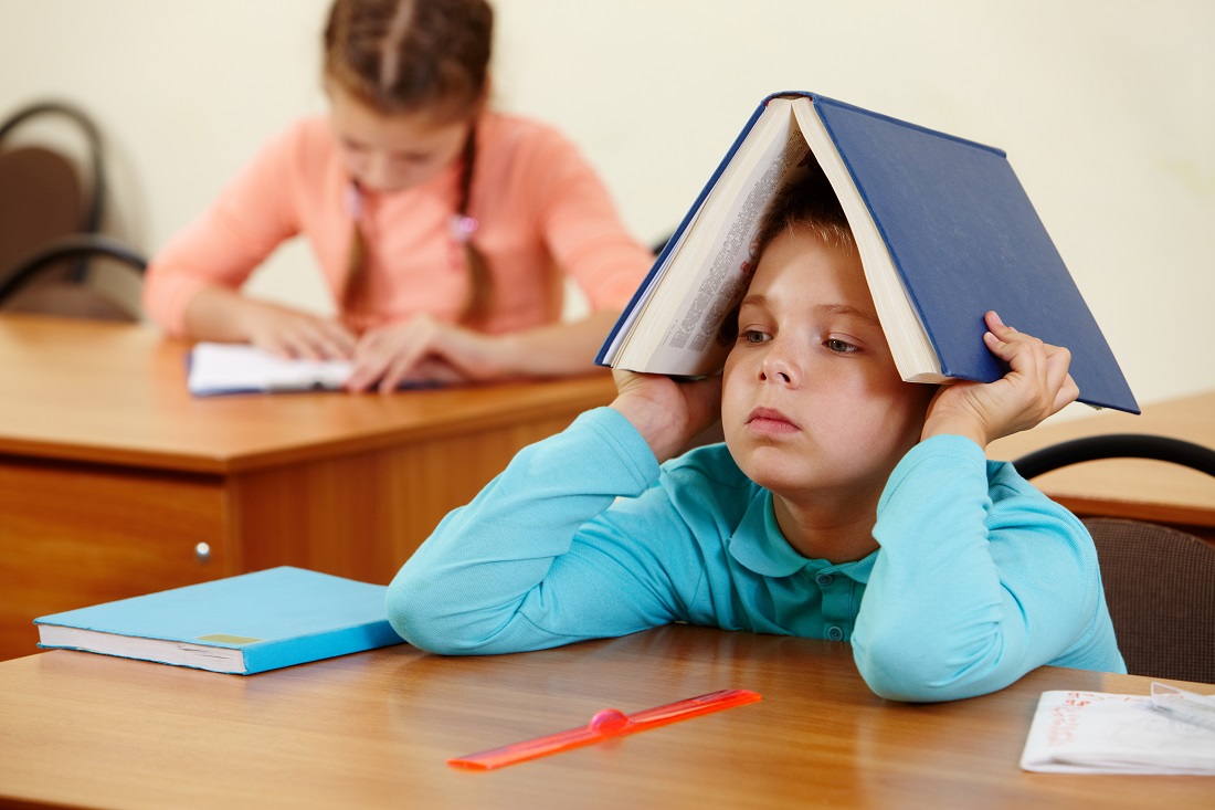 Ordforrådet. Bildet viser en gutt med ei bok på hodet. I bakgrunnen ei jente som leser.