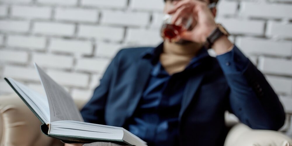 Utdanning. Bildet viser mann med en bok og et glass med drikke.