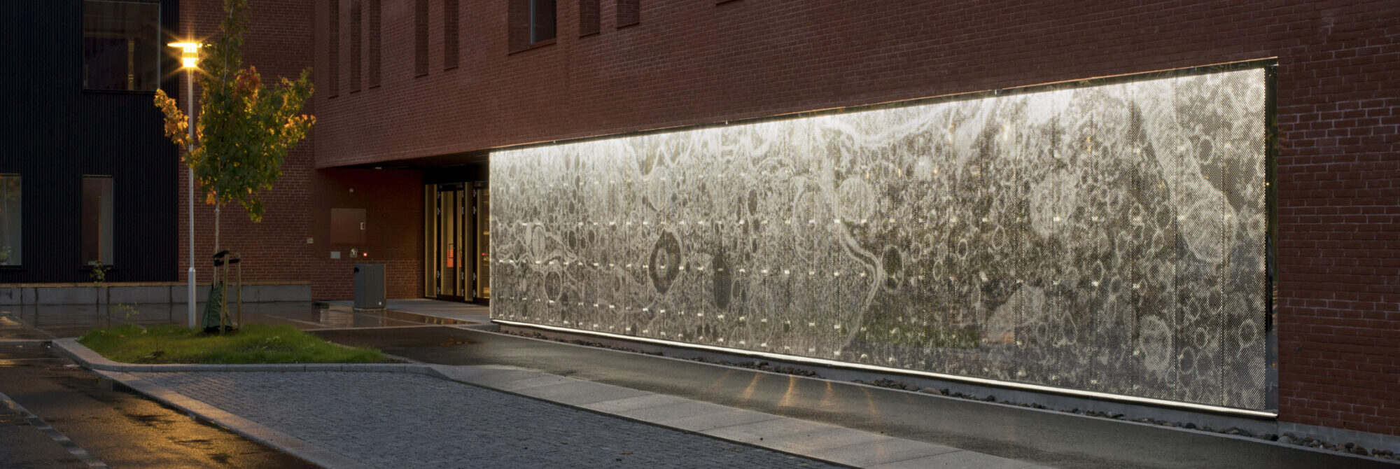 Bilde som viser kunstverk i stål langs en murvegg