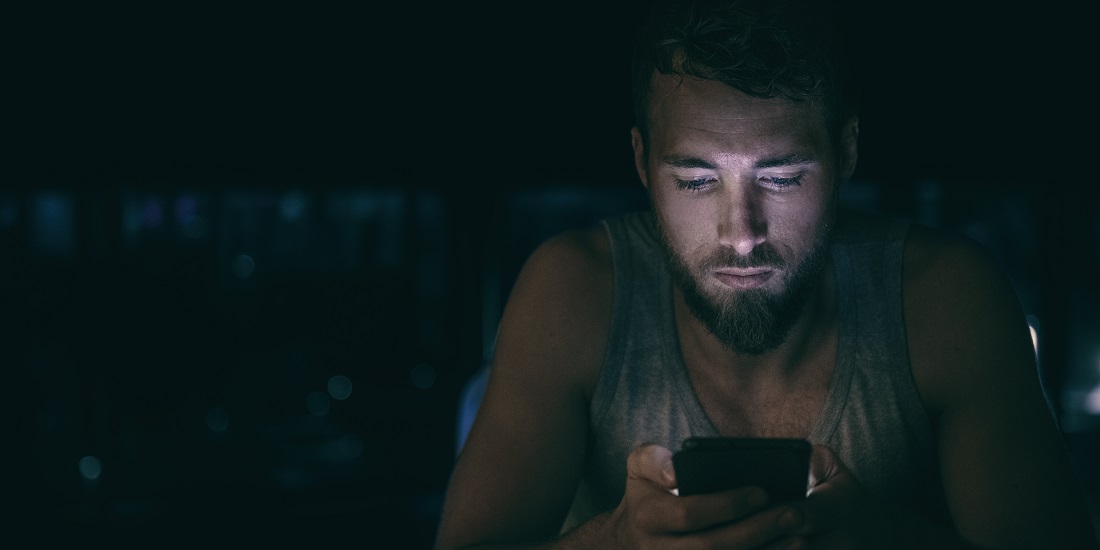 Sosiale medier. Bildet viser en mann i mørket med en telefon.
