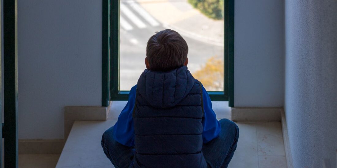 Ny rapport om barnevern. istock illustrasjonsfoto av gutt som ser ut av vindu, med ryggen til,
