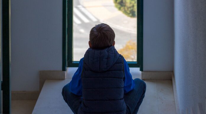 Ny rapport om barnevern. istock illustrasjonsfoto av gutt som ser ut av vindu, med ryggen til,