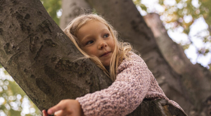 Jente som klatrer i et tre og hviler ansiktet mot trestammen. Illustrasjon til artikkel om jenter, ADHD og angst