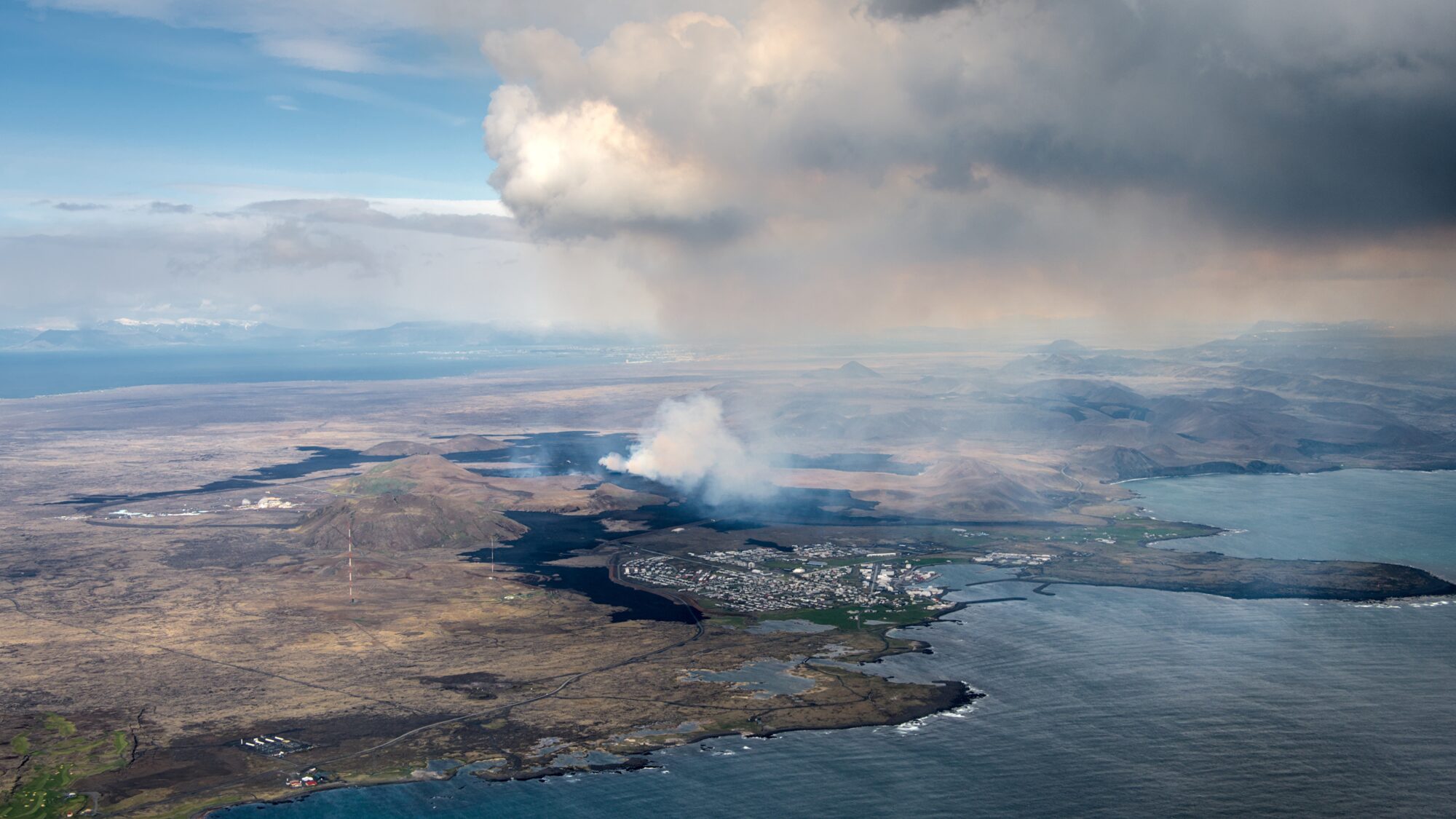 Bildet som viser vulkansk røyk over byen Grindavik på Island. Bildet illustrerer en artikkel om jordvoller som beskyttelse mot lava.